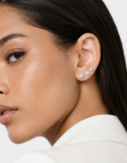 Close-up of a woman wearing diamond stud earrings with a neutral background