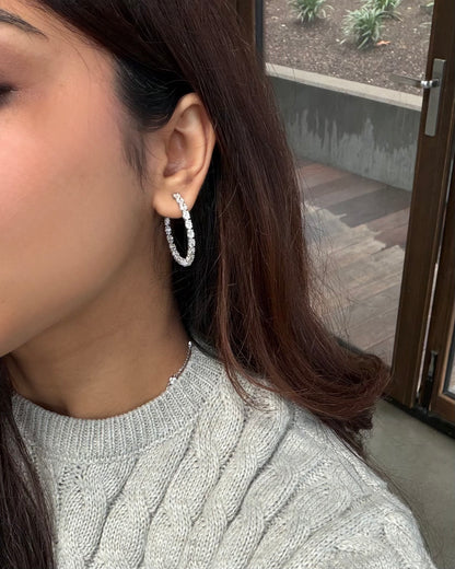 Model wearing oval diamond hoop earrings in white gold #white gold