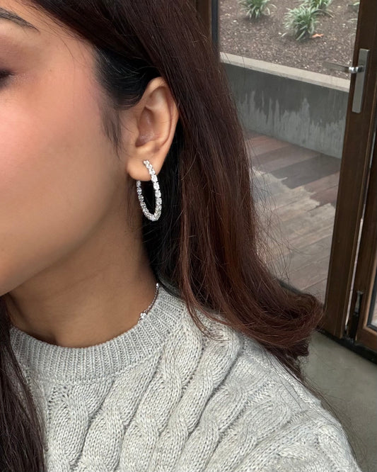 Model wearing oval diamond hoop earrings in white gold #white gold